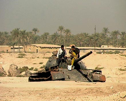 Jugendliche spielen auf kontaminiertem Panzer auf dem Schlachtfeld von Abu Khassib bei Basra